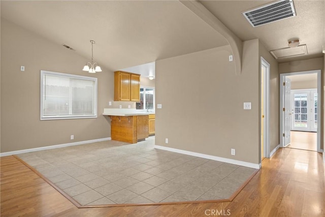 interior space featuring light wood finished floors, visible vents, light countertops, lofted ceiling, and a kitchen breakfast bar