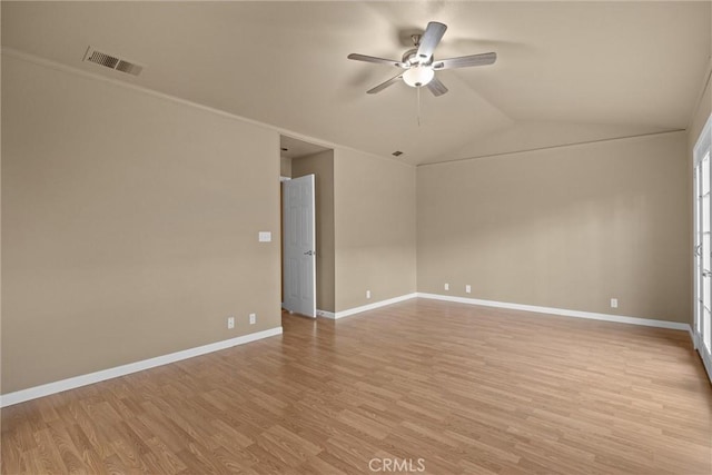 empty room with baseboards, visible vents, light wood-style flooring, ceiling fan, and vaulted ceiling