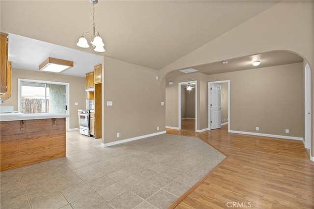 unfurnished living room with an inviting chandelier, vaulted ceiling, arched walkways, and a sink