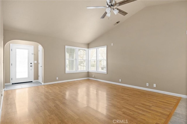 interior space with vaulted ceiling, light wood-style flooring, and arched walkways