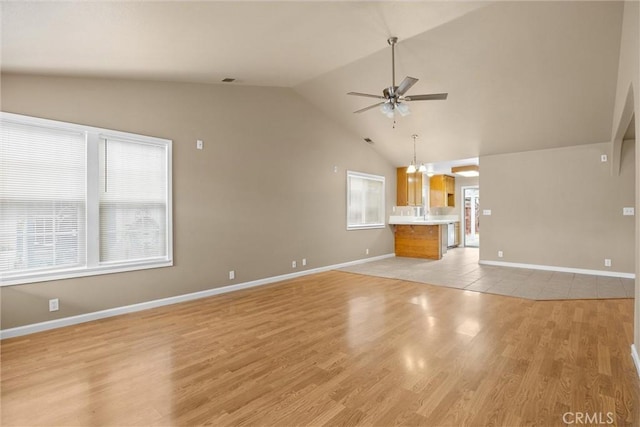 unfurnished living room featuring light wood-type flooring, baseboards, high vaulted ceiling, and ceiling fan