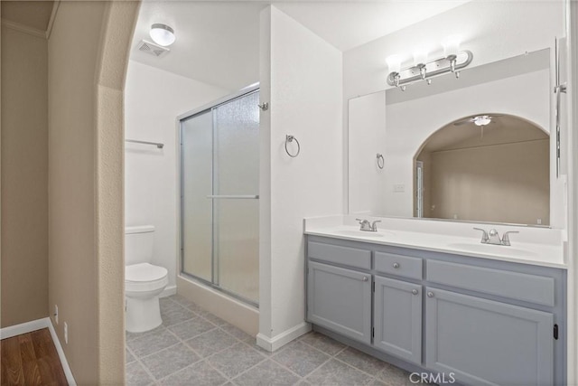 bathroom featuring toilet, a stall shower, and a sink