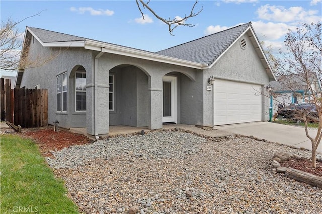 view of front of home featuring fence, roof with shingles, stucco siding, driveway, and an attached garage