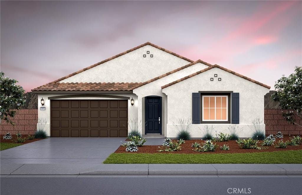 mediterranean / spanish-style home with fence, a tiled roof, stucco siding, a garage, and driveway