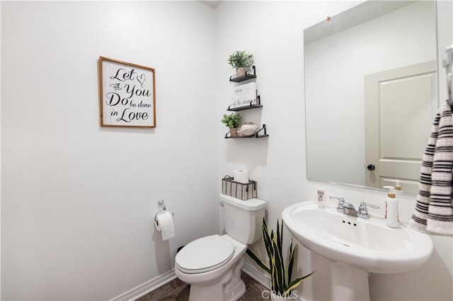 bathroom featuring a sink, baseboards, toilet, and tile patterned flooring