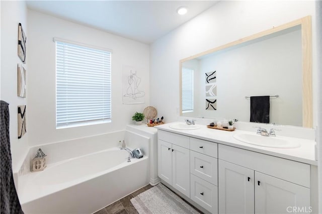 bathroom featuring a sink, a bath, and double vanity