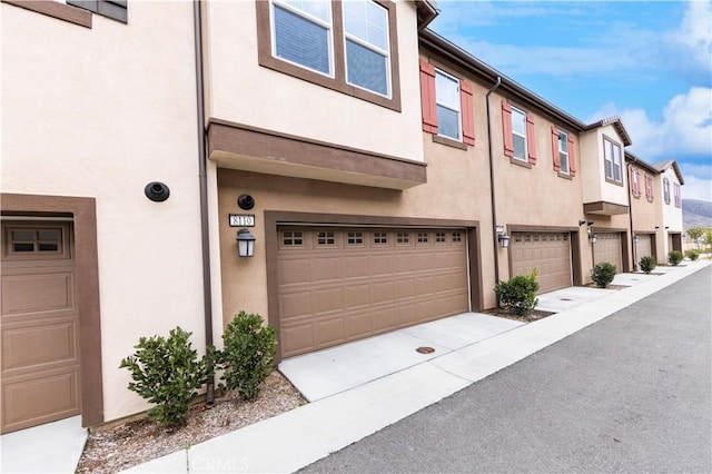 exterior space with a garage, a residential view, and stucco siding