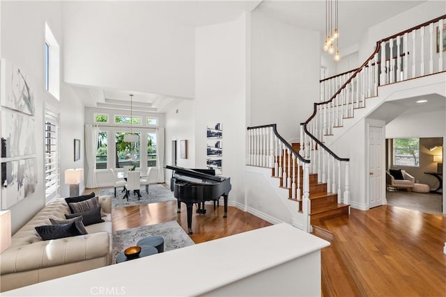 living room featuring stairway, a healthy amount of sunlight, a towering ceiling, and wood finished floors