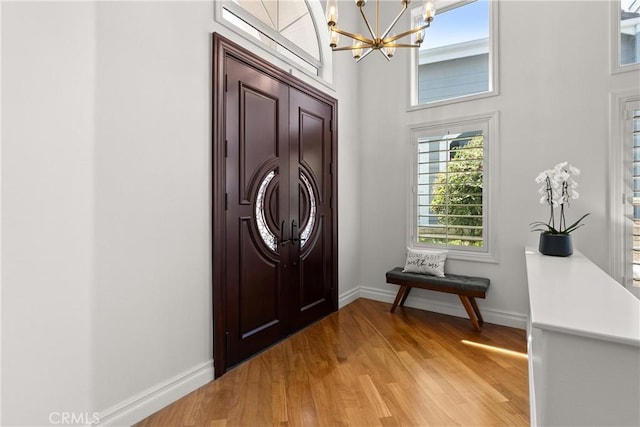 entrance foyer featuring light wood finished floors, a chandelier, and baseboards