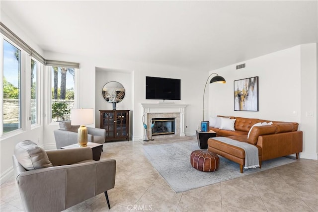 living room with light tile patterned floors, visible vents, baseboards, and a premium fireplace