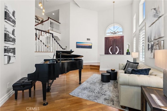 interior space featuring stairway, wood finished floors, baseboards, and a towering ceiling