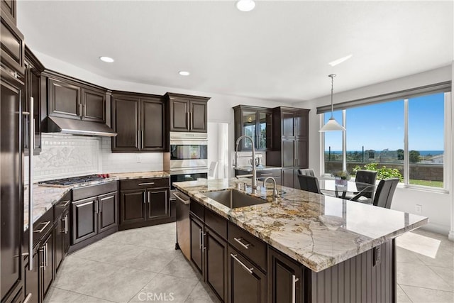 kitchen featuring under cabinet range hood, decorative backsplash, appliances with stainless steel finishes, light tile patterned flooring, and a sink