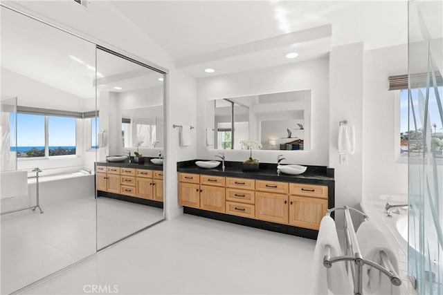 bathroom featuring a soaking tub, double vanity, recessed lighting, a sink, and vaulted ceiling