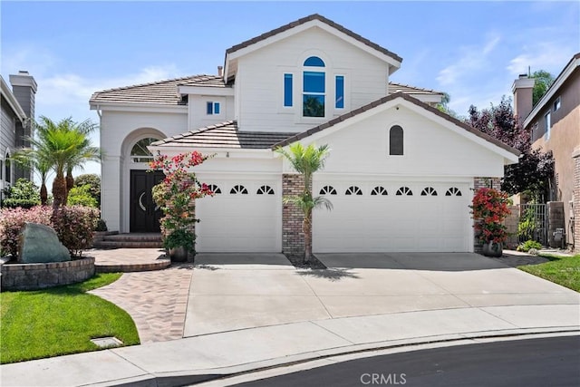 mediterranean / spanish house featuring a garage, brick siding, concrete driveway, and a tiled roof