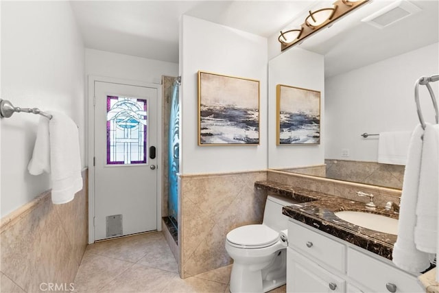 full bath with tile patterned floors, tile walls, a shower stall, wainscoting, and vanity