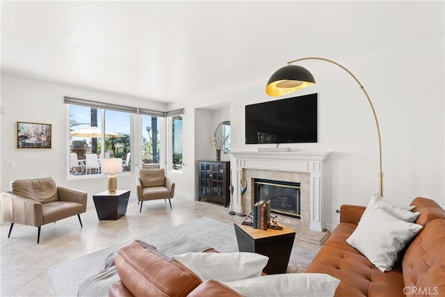 living room featuring light tile patterned flooring, a tile fireplace, and baseboards