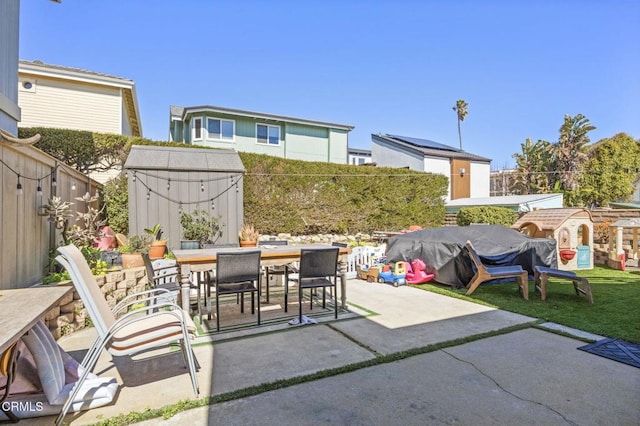 view of patio featuring outdoor dining space, an outbuilding, area for grilling, a fenced backyard, and a storage shed