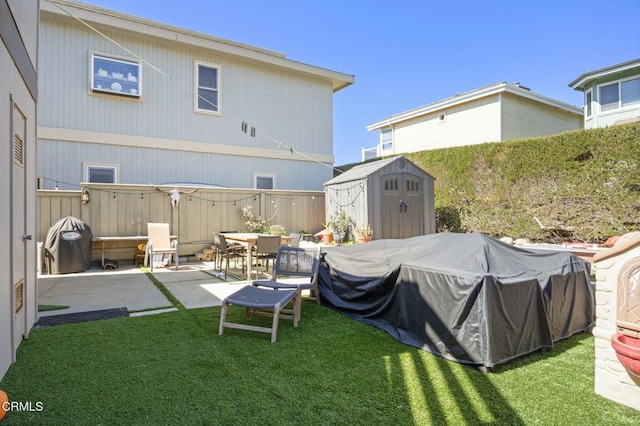 back of property with an outbuilding, fence, a yard, a storage shed, and a patio area