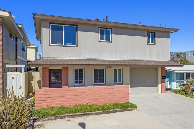 view of front of property with concrete driveway, an attached garage, fence, and a shingled roof