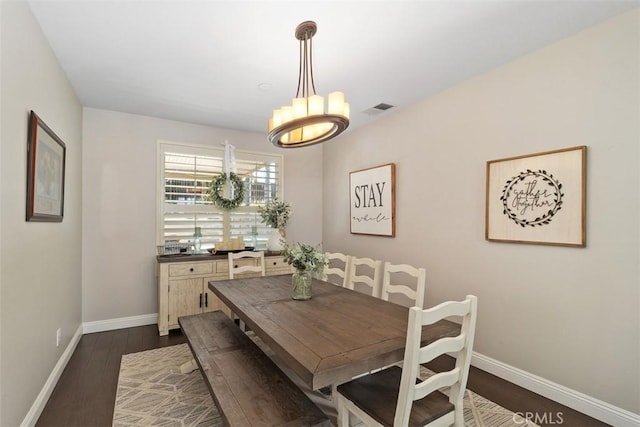 dining room with dark wood finished floors, visible vents, a chandelier, and baseboards