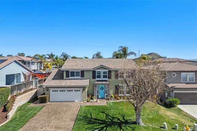 traditional-style home with stucco siding, fence, concrete driveway, a front yard, and a tiled roof