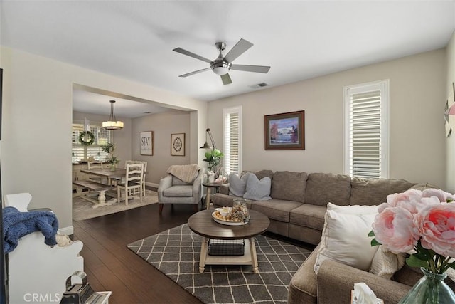 living room with hardwood / wood-style floors, a ceiling fan, visible vents, and baseboards