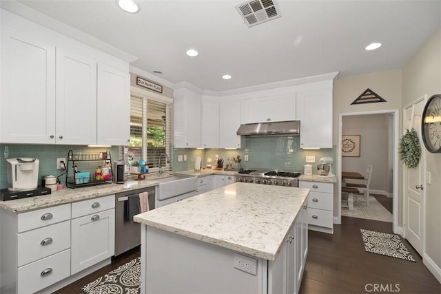 kitchen featuring visible vents, under cabinet range hood, dishwasher, white cabinetry, and a sink