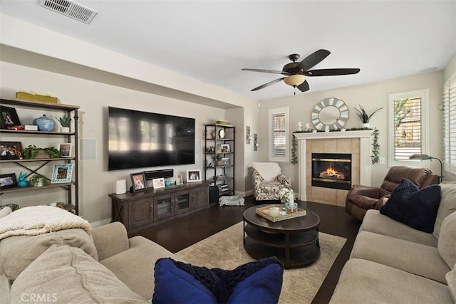 living area with ceiling fan, visible vents, wood finished floors, and a tile fireplace