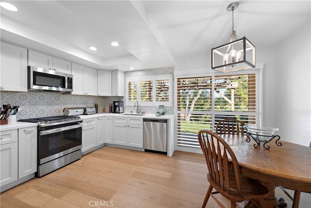 kitchen featuring a sink, stainless steel appliances, backsplash, and light wood-style flooring