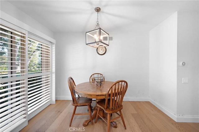 dining area featuring a chandelier, light wood-type flooring, and baseboards