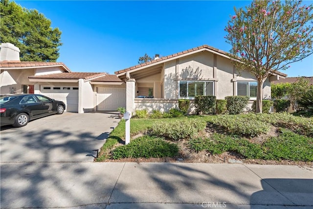 view of front facade with concrete driveway, an attached garage, and stucco siding