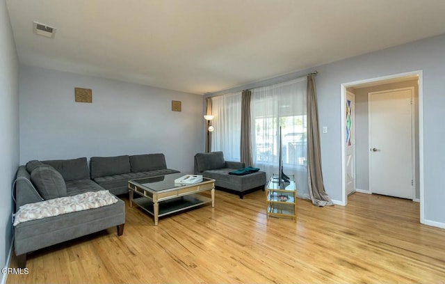 living area with visible vents, light wood-type flooring, and baseboards