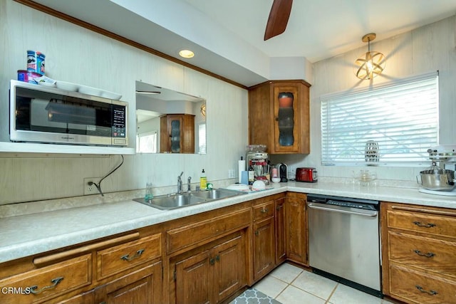 kitchen featuring a sink, stainless steel appliances, brown cabinetry, light countertops, and glass insert cabinets