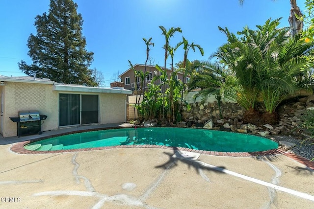 outdoor pool with area for grilling, a patio, and fence