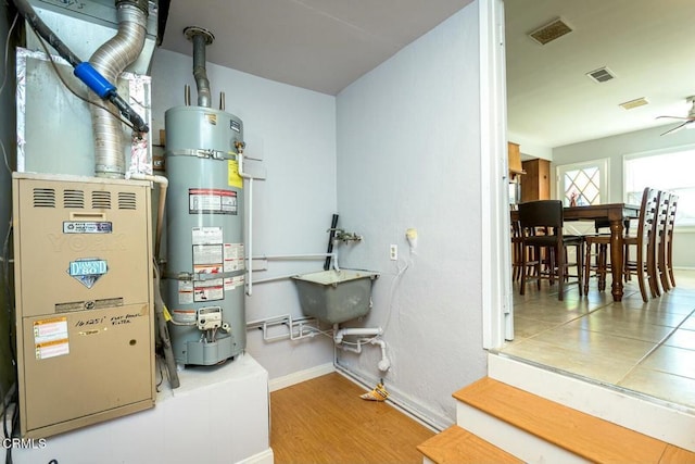 utility room with heating unit, visible vents, and water heater