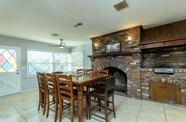 tiled dining area featuring a ceiling fan, a fireplace, and visible vents