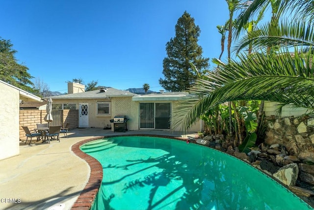 view of swimming pool featuring a patio, area for grilling, and fence