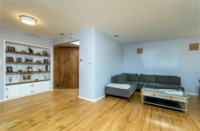 living room with visible vents, baseboards, and light wood finished floors