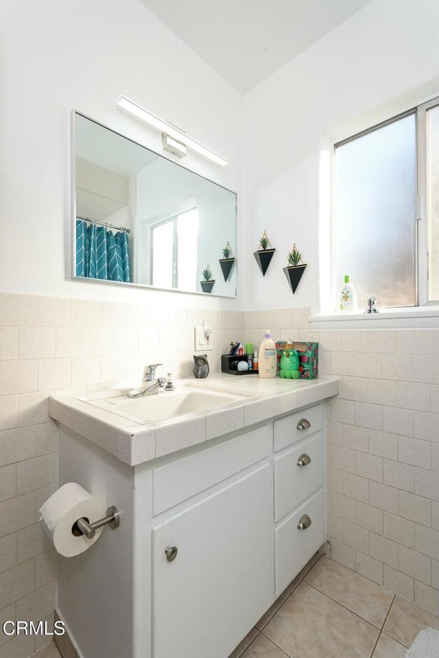 full bathroom with vanity, tile walls, tile patterned floors, and wainscoting