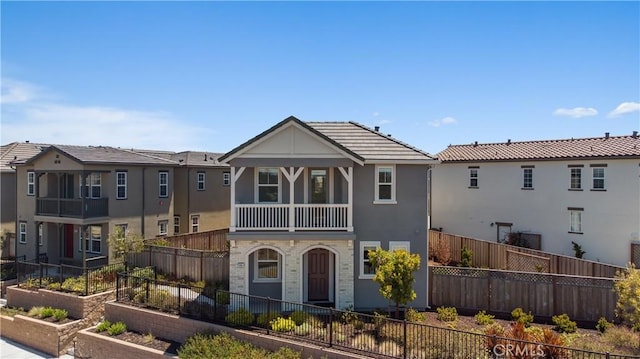 view of front facade with a balcony, a garden, stucco siding, a fenced front yard, and a tiled roof