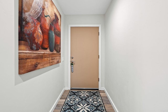 doorway with baseboards and wood finished floors