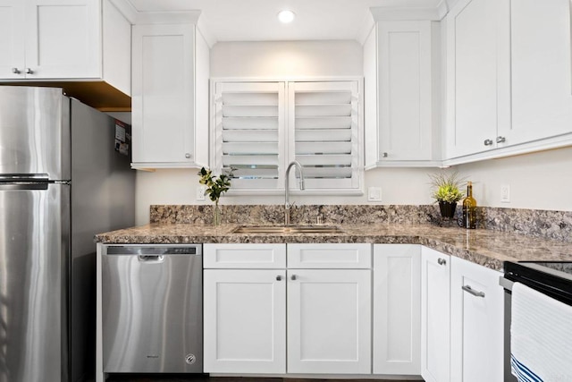 kitchen with dark countertops, a sink, stainless steel appliances, white cabinets, and recessed lighting