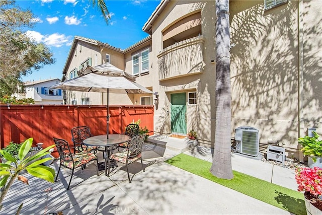 view of patio with outdoor dining area, central AC, and fence