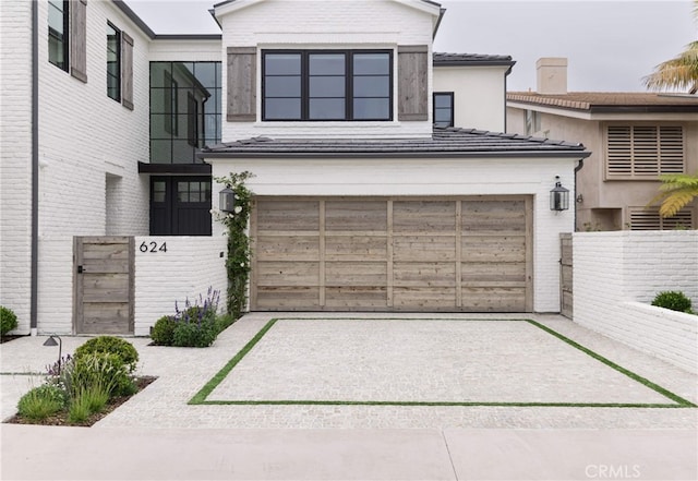 view of front of home with concrete driveway, fence, and brick siding