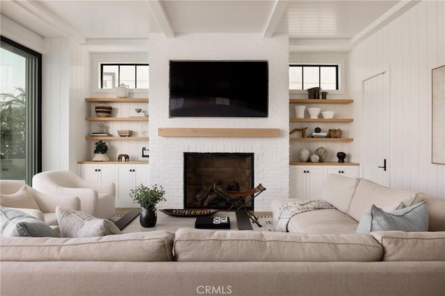 living room with beam ceiling, built in features, and a fireplace