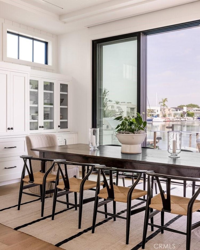 dining room featuring a water view and light wood-style floors