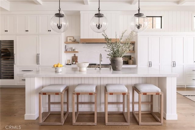 kitchen with open shelves, beverage cooler, and light wood-type flooring