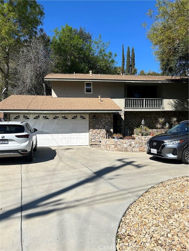 view of front of house featuring concrete driveway, an attached garage, stone siding, and stucco siding