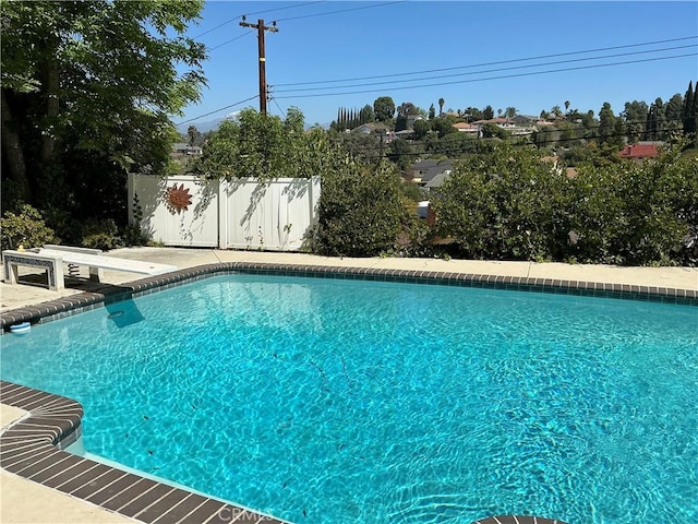 view of swimming pool with a diving board, a fenced in pool, a patio area, and fence