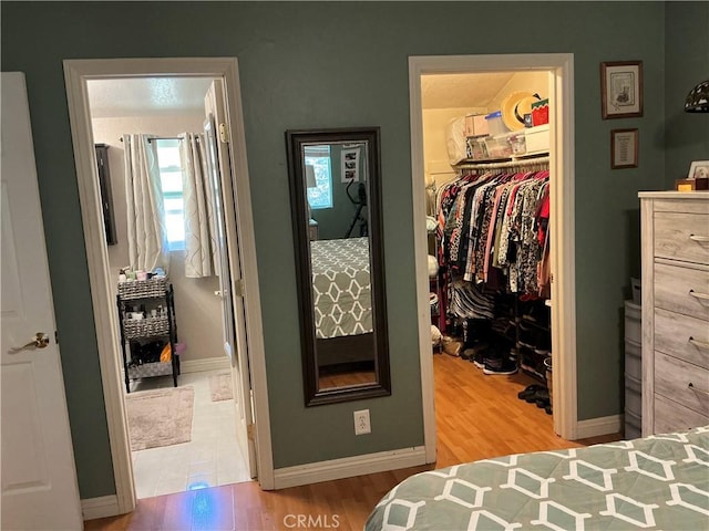 bedroom featuring a closet, baseboards, wood finished floors, and a spacious closet